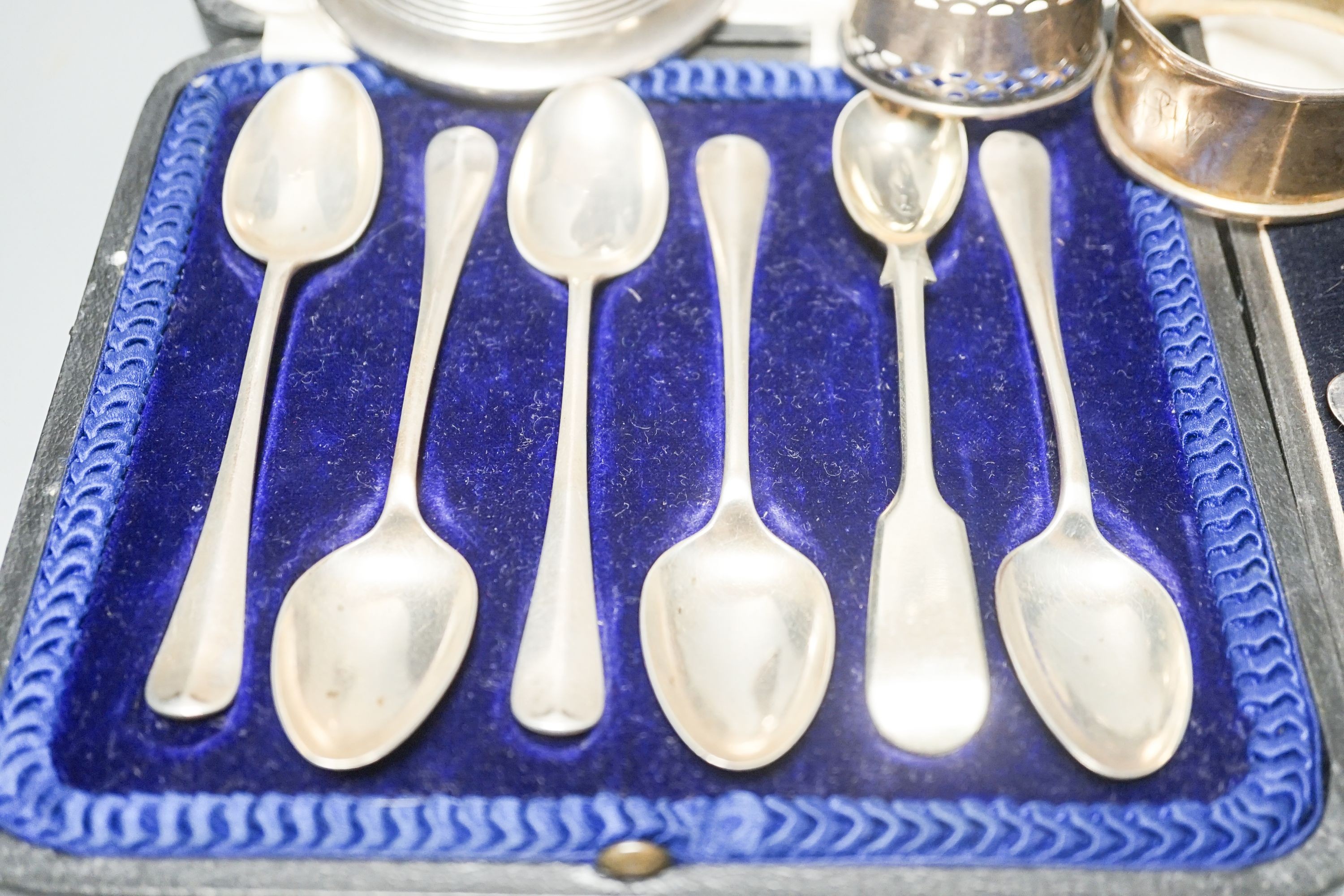 A cased set of six silver teaspoons, a cased christening set, three silver napkin rings and a silver dwarf candlestick.